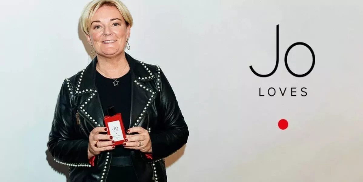 This is a banner for Jo love with the founder Ms Jo Malone CBE holding a perfume bottle.